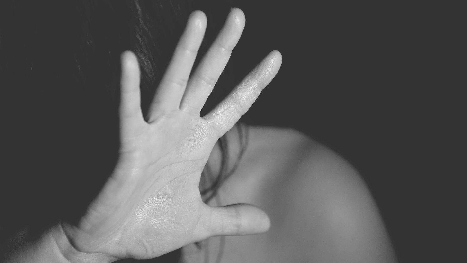 Eine Frau, deren Gesicht nicht zu sehen ist, hebt die Hand in einer Abwehrhaltung
