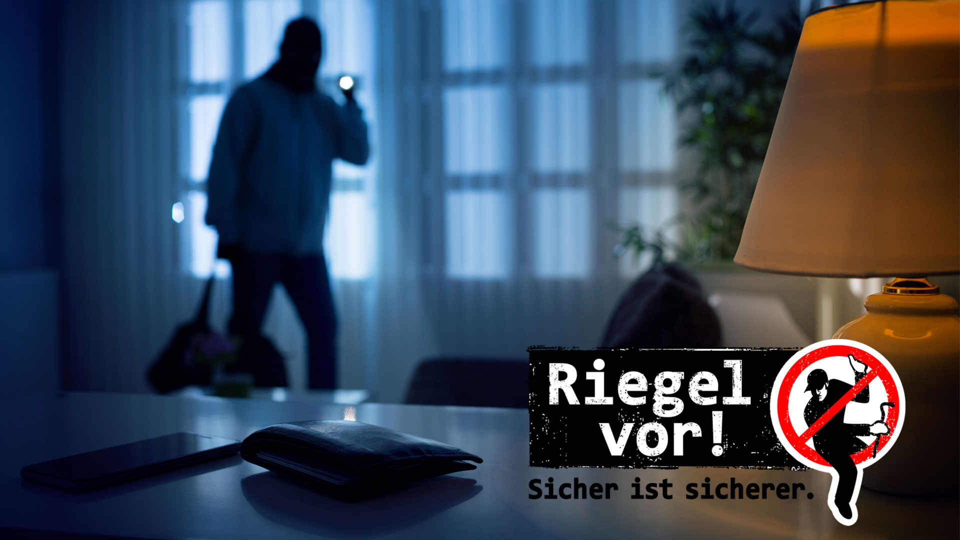 Ein dunkler Raum. Im Hintergrund sieht man einen Einbrecher mit Taschenlampe. Im Vordergrund liegt eine Geldbörse und ein Handy auf einem Tisch