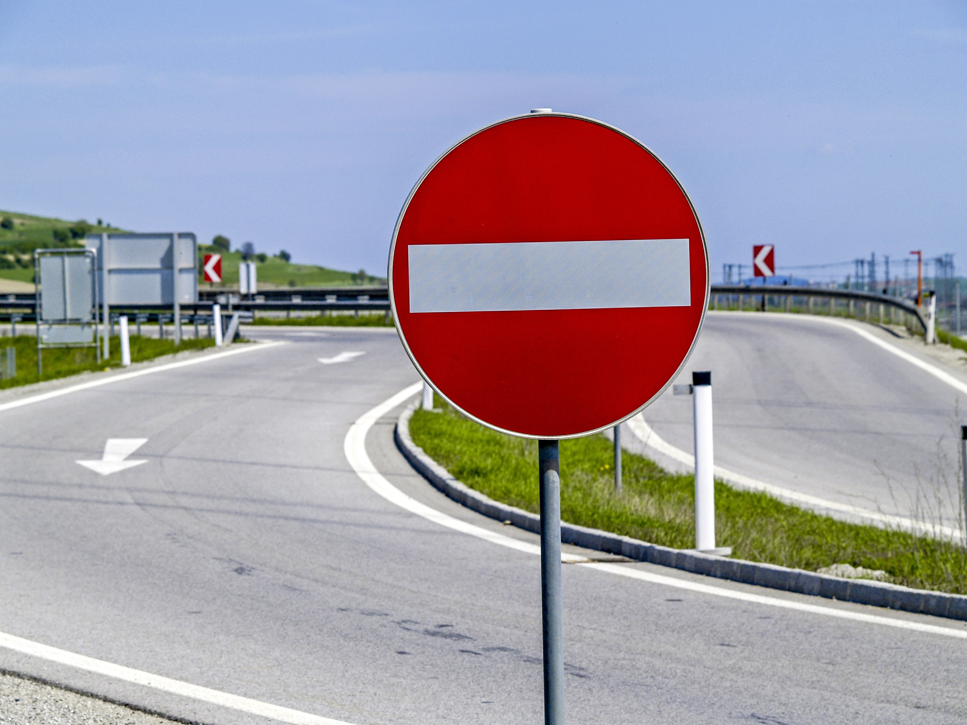 The photo shows the traffic sign "No entry" in the foreground and a highway exit in the background.