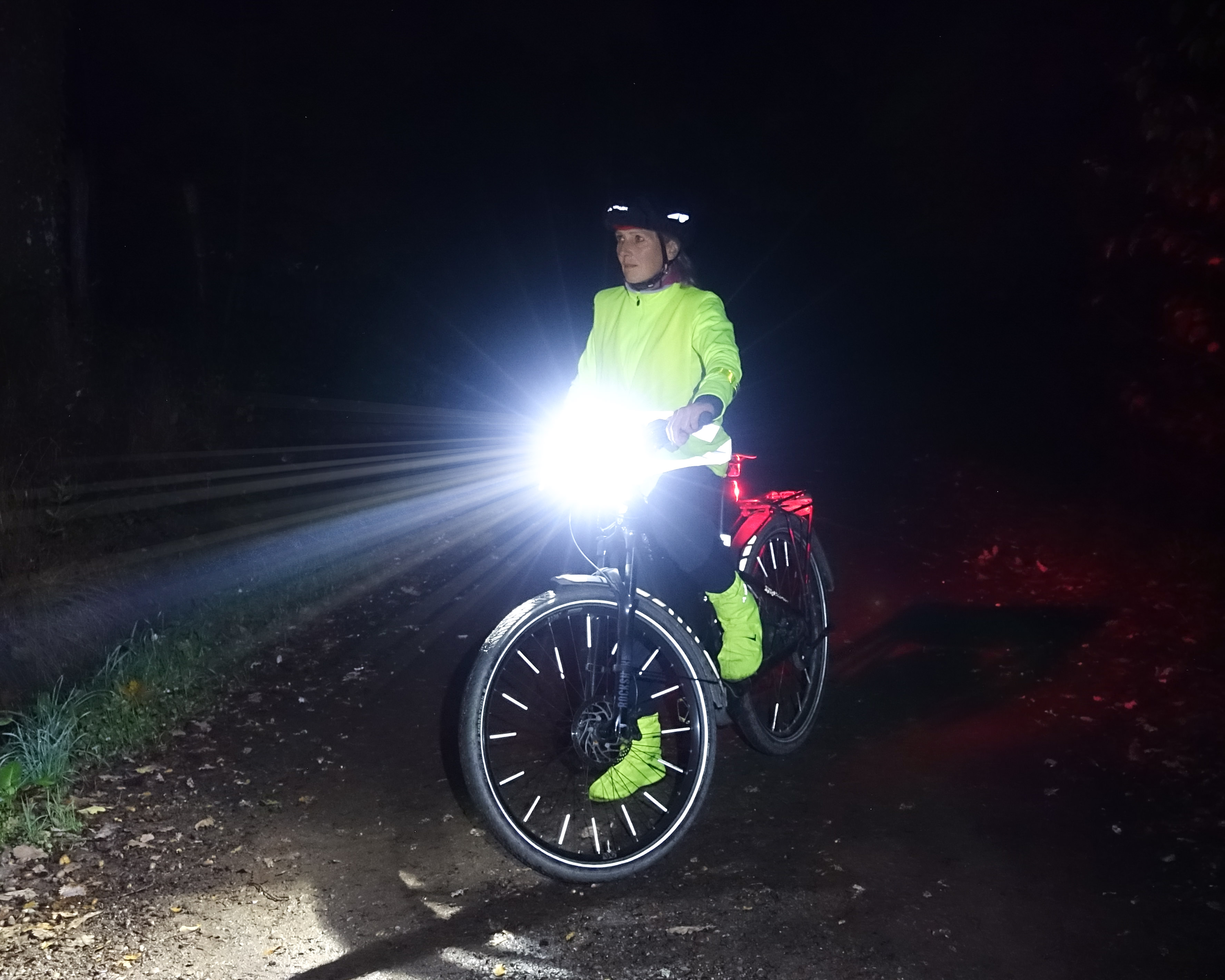 Radfahrer bei Dunkelheit mit Leuchtkleidung und hellem Scheinwerfer