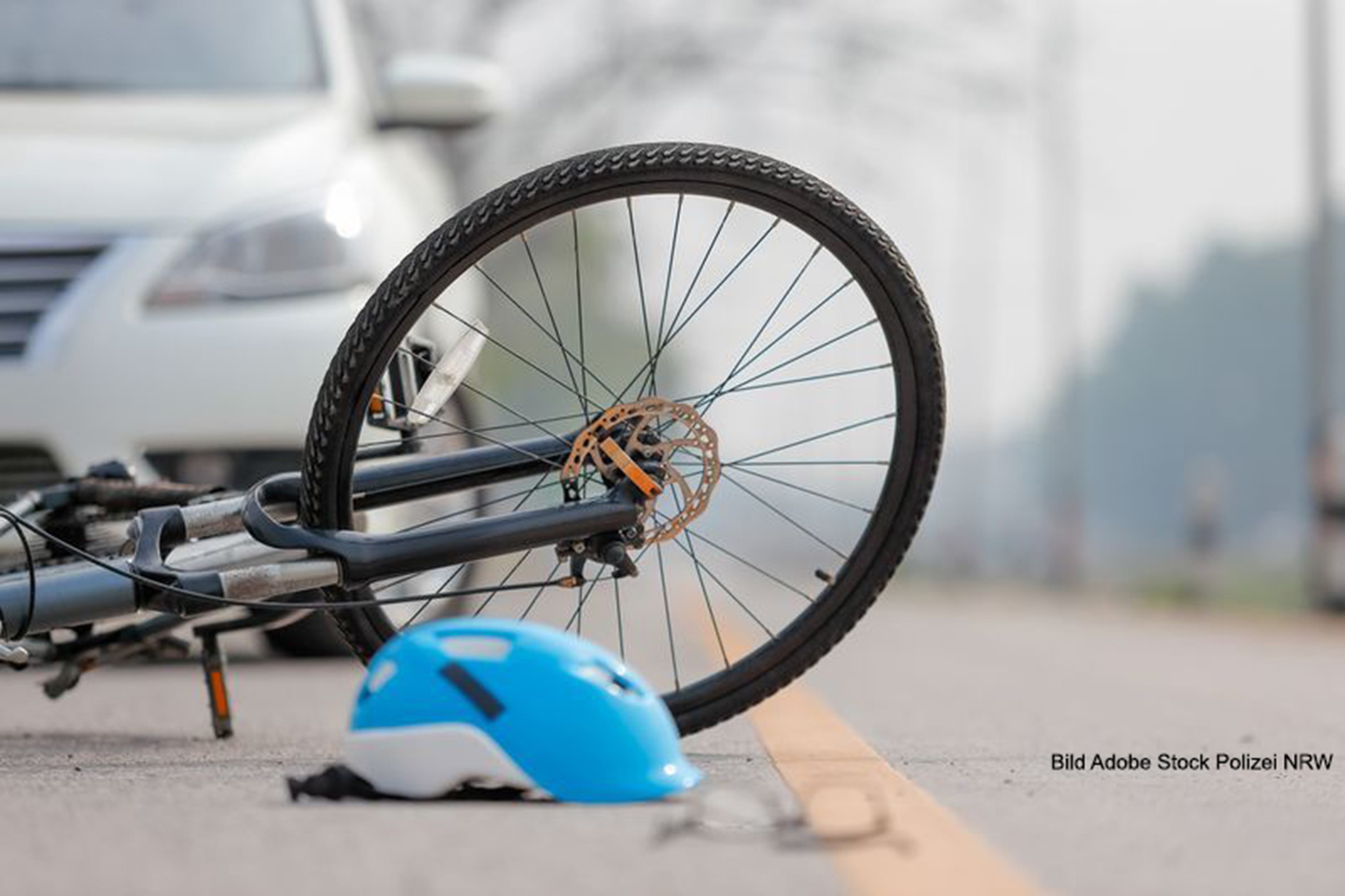 recumbent bicycle; bicycle helmet and a bicycle in the foreground, car in the background