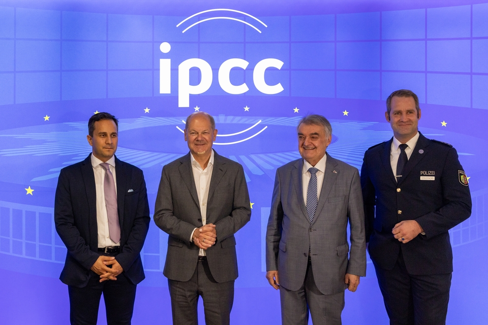 Staatssekretär Mahmut Özdemir, Bundeskanzler Olaf Scholz, Innenminister Herbert Reul, IPCC 2024-Leiter Oliver Strudthoff stehen vor einer blauen Wand mit dem Logo des IPCC 2024