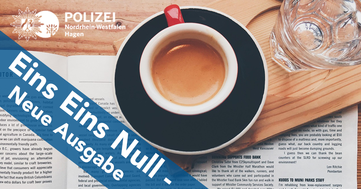 Eine Zeitung liegt auf einem Holztisch, darauf eine Kaffeetasse. Blick von oben