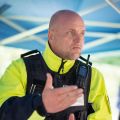 Gerd Buse, erster Polizeihauptkommissar und Wachleiter der Autobahnpolizei Broichweiden ist leicht schräg im Portrait zu sehen. Er gestikuliert mit der Hand. Er trägt neon-gelbe und dunkelblaue Uniform..