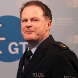 Volker Pfeiffer im Hintergrund das Logo der Polizei Gütersloh