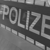 Close-up vom Schriftzug "Polizei" auf einem Polizeibulli in Schwarzweiß