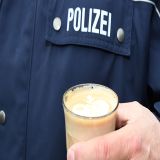 Person mit Glas in der Hand in dem Kaffee ist. Die Person ist ein Polizist.