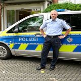 Martin Huber steht vor einem Streifenwagen