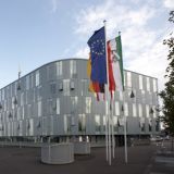 Das Gebäude der Polizei Mettmann mit vier geflaggten Fahnenmasten im Vordergrund.