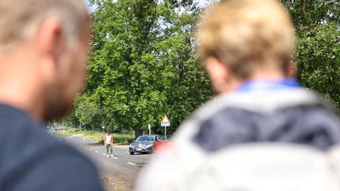 Zwei Personen sind von hinten zu sehen, wie sie in Richtung eines Mannes schauen.
