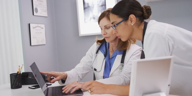 Zwei medizinische Fachangestellte schauen auf einen Laptop
