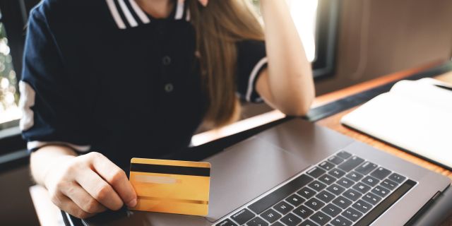 Frau sitzt mit Kreditkarte vor dem Computer