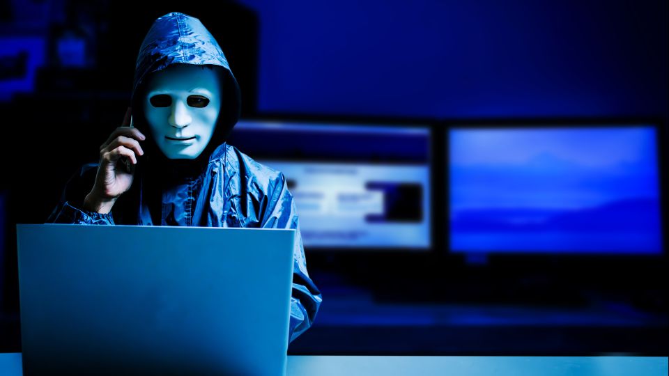 Anonymer Anrufer mit Maske am Computer