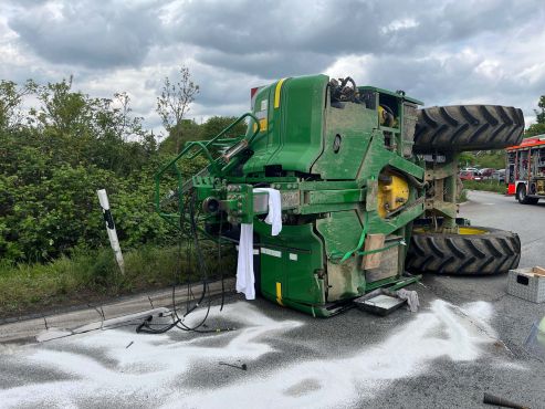 Anhänger eines Traktors liegt auf der Seite. Auf der Straße liegt Streugut.