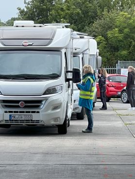 Eine Schlange von Campingmobilen. Zwei Polizeibeamtinnen stehen an den Fahrerfenstern.