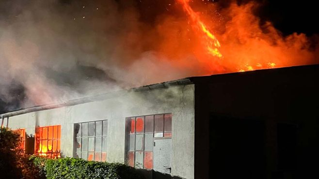 das Bild zeigt ein brennendes Gebäude aus dem Dach schlagen Flammen